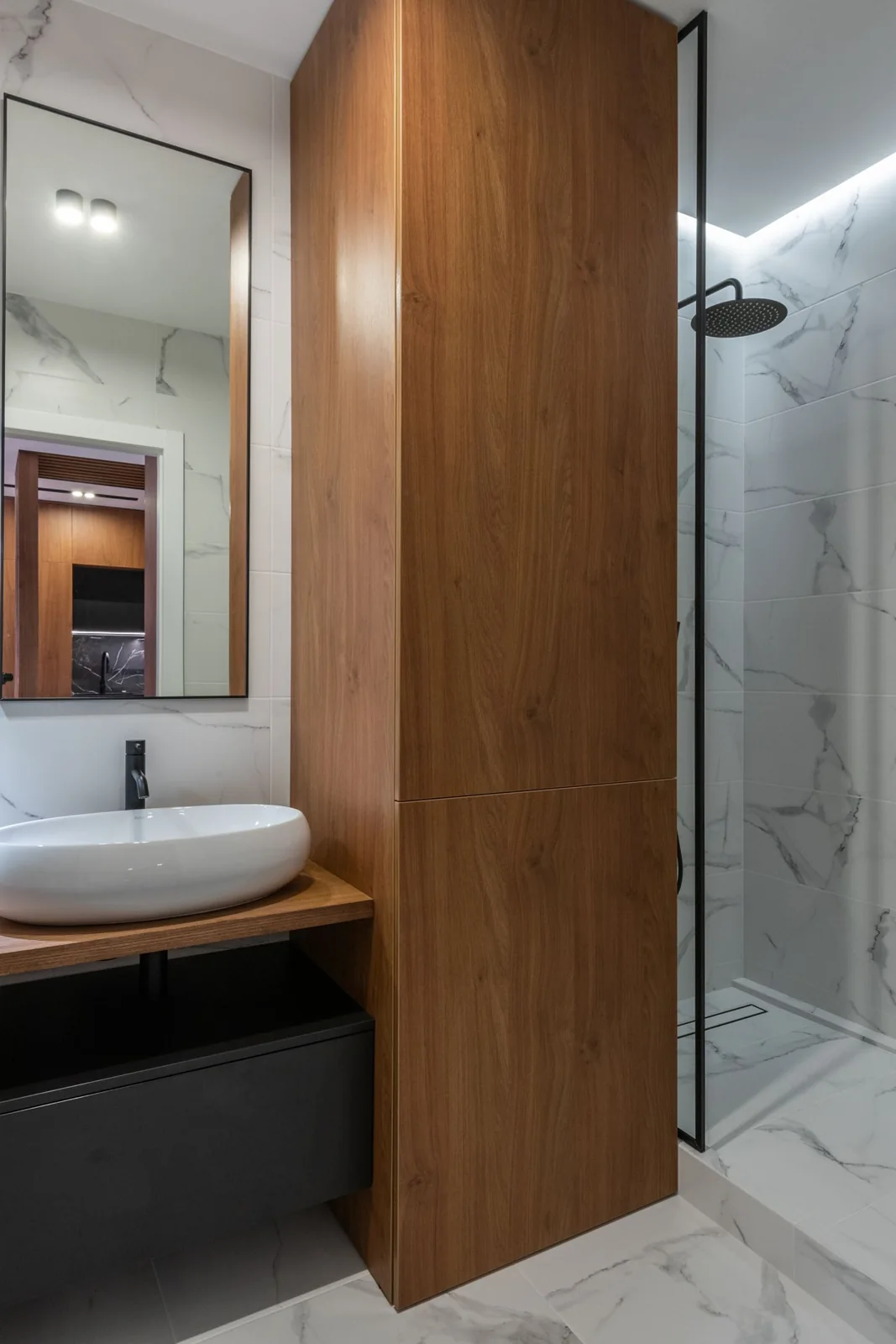 Area wastafel dan shower kaca dengan lemari kayu setinggi ruangan