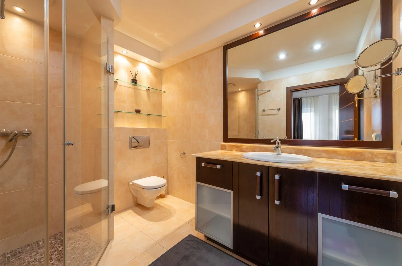Area wastafel luas dan shower kaca dalam nuansa krem hangat