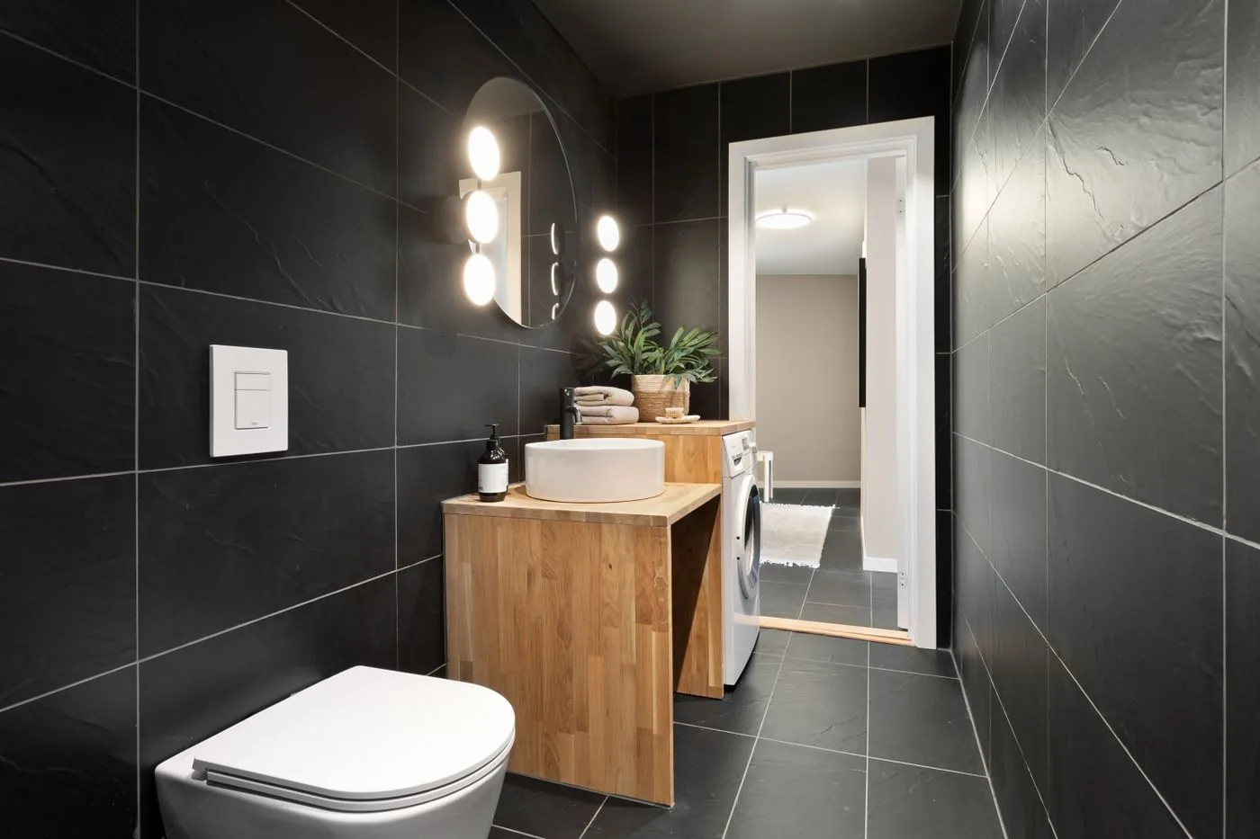 Modernes Gäste-WC mit Holzwaschtisch und dunklen Fliesen