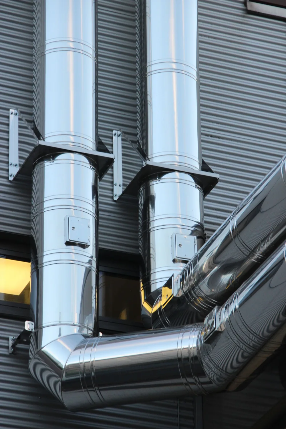 現代的な商業建築の外壁にある光沢のある換気ダクト