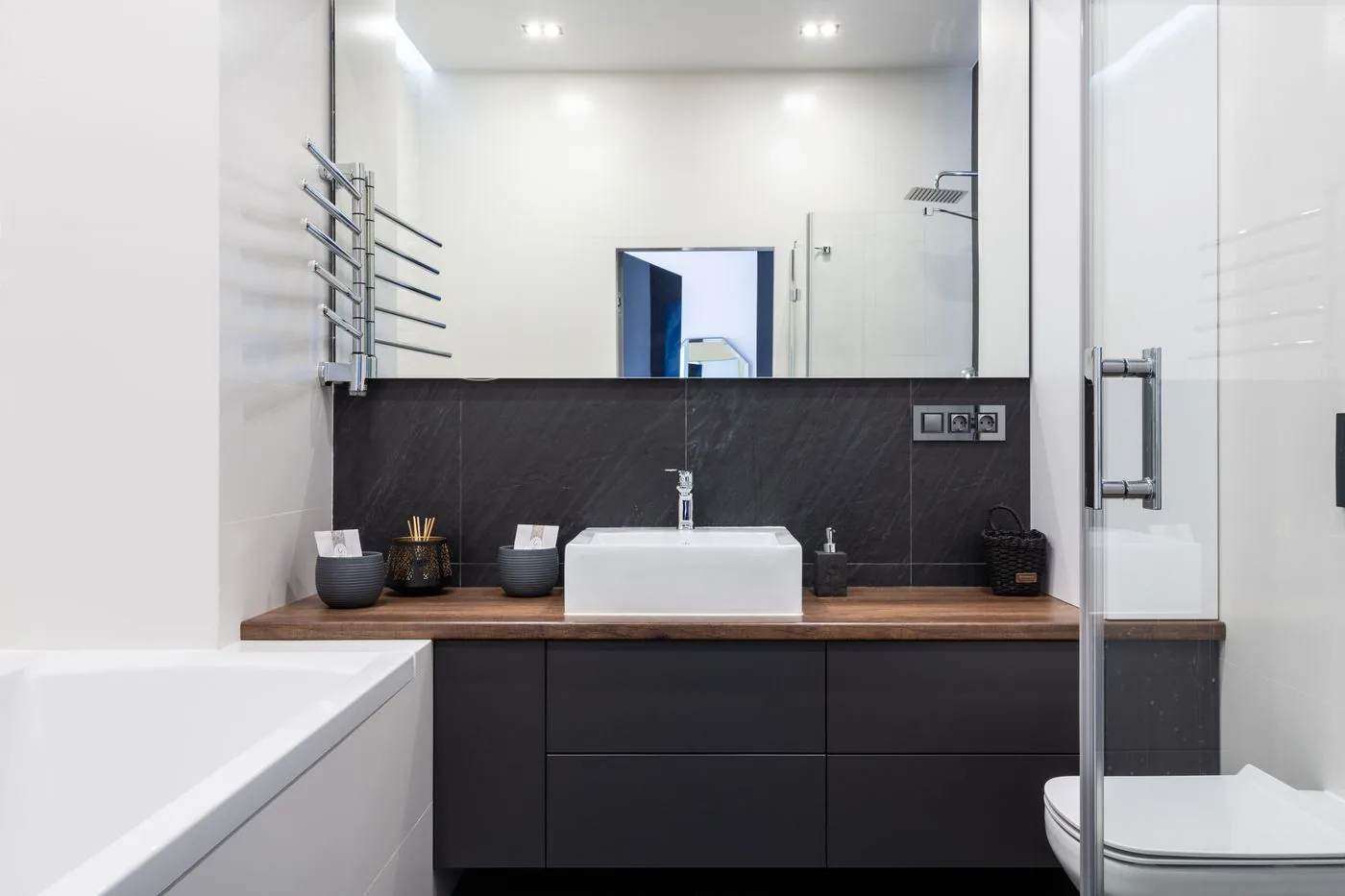 Kamar mandi ringkas dengan meja wastafel gelap dan sekat kaca