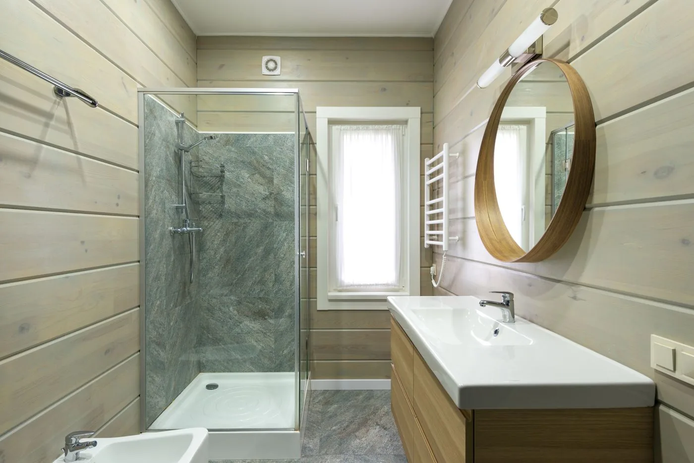Badezimmer mit Rundspiegel und verglaster Dusche