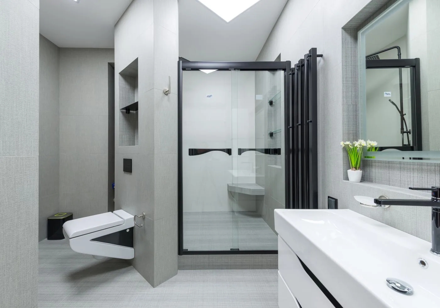 Desain kamar mandi tegas dengan sekat pancuran hitam