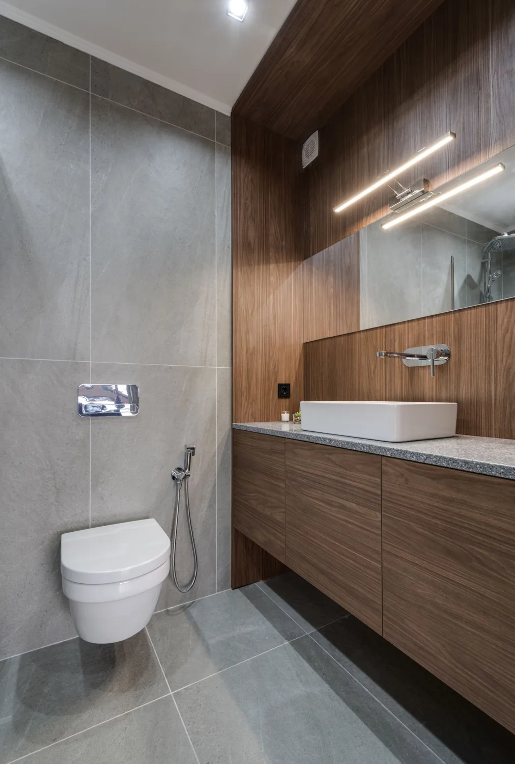 Wandhängendes WC neben einem Holzwaschtisch