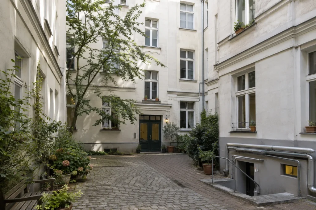Begrünter Innenhof eines Mehrfamilienhauses mit sichtbarer Haustechnik